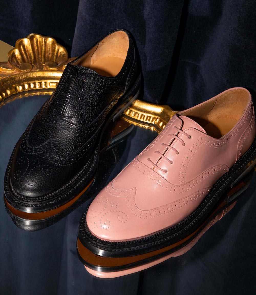Estee in black pebble grain leather and Estee in solid soft pink smooth leather sit in a setting of lush navy velvet and gold