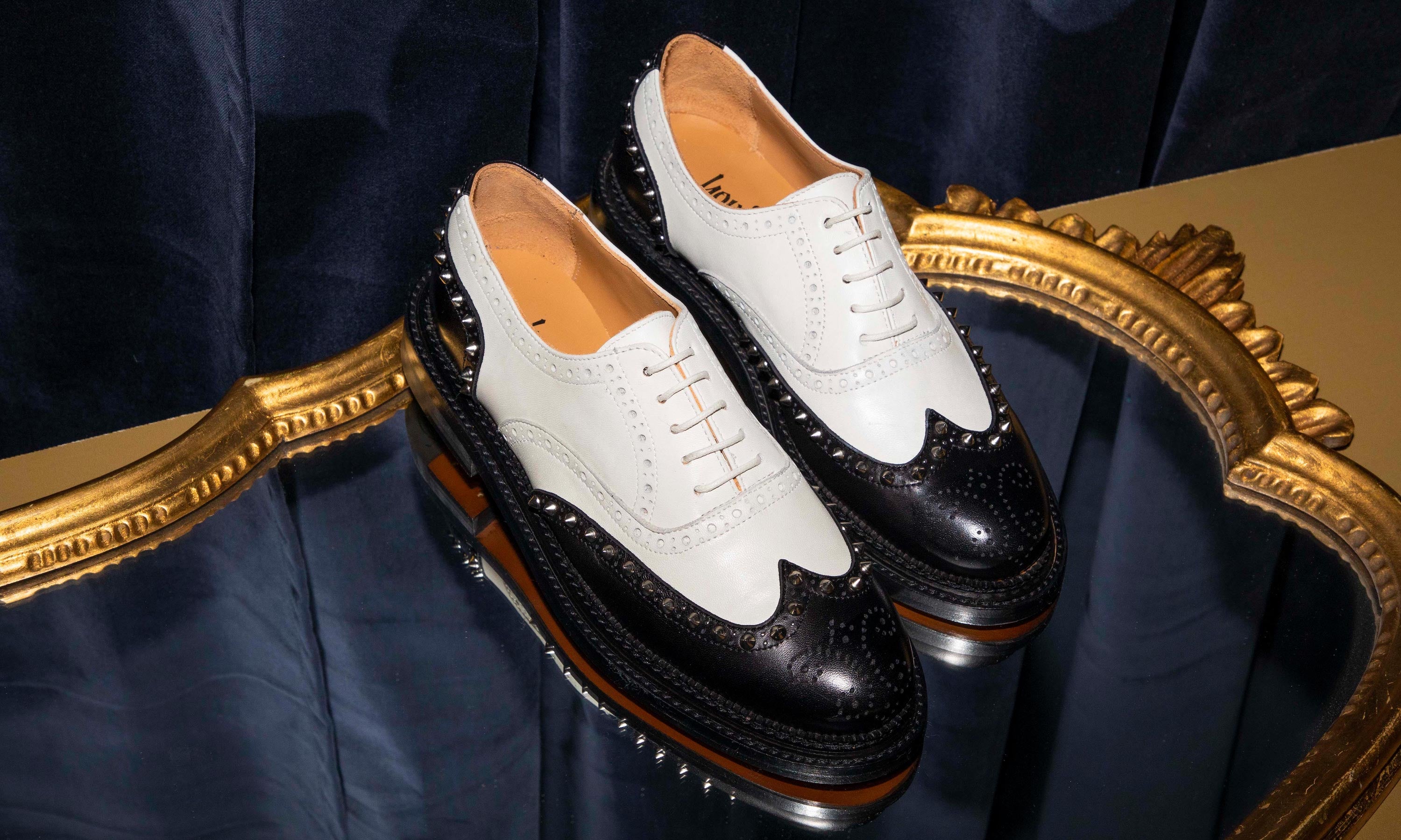 jameela black and white oxford spectator sits in a decadent setting of dark blue velvet and gold